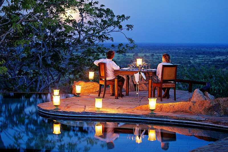 A couple in robes on a private deck at sunrise, looking out over open plains