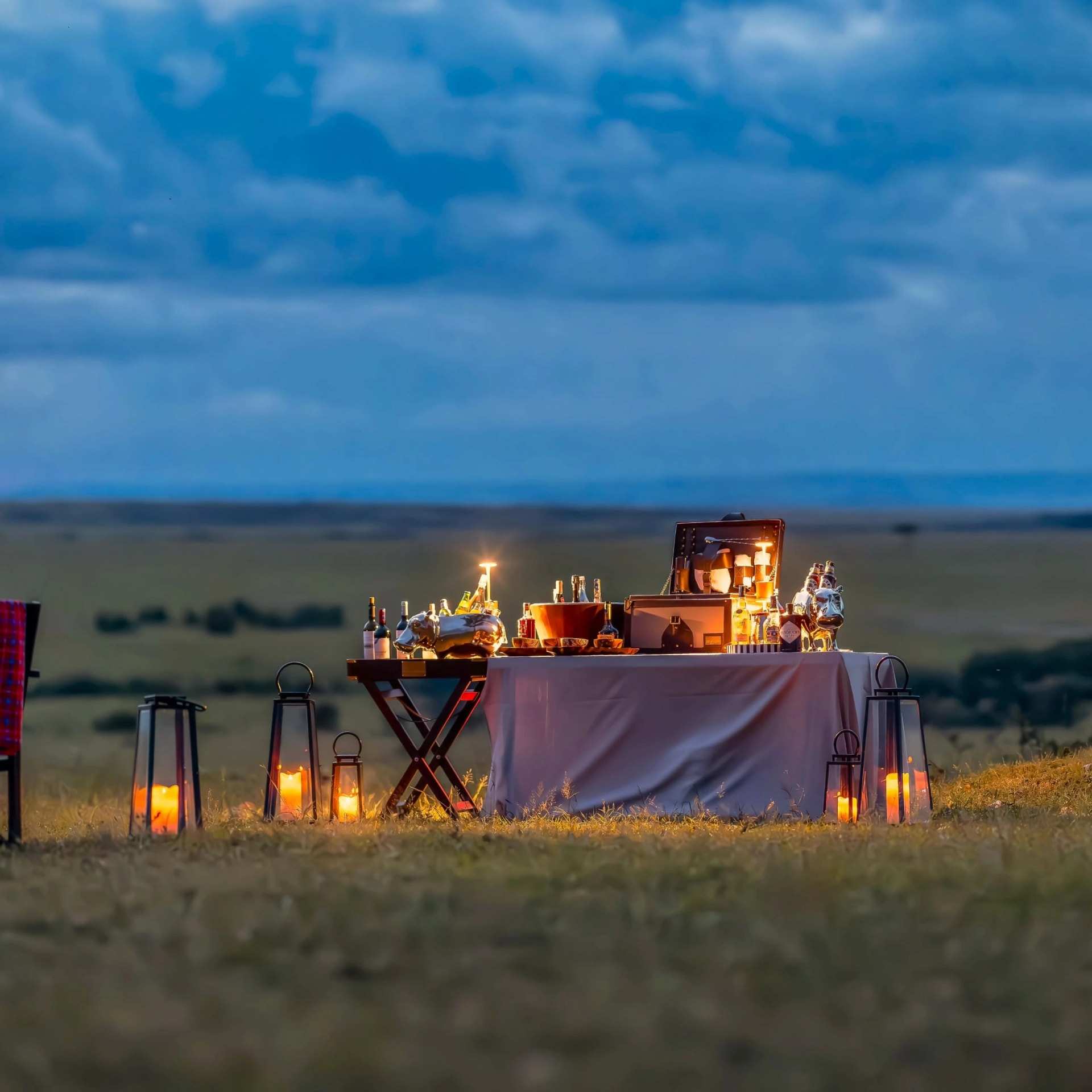 A candlelit dinner table set out on the plains at dusk